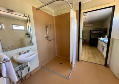 Bathroom of family cabin showing inside of shower including removable handset nozzle and sink.