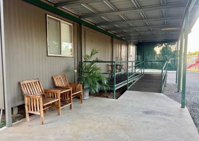 outdoor undercover area showing ramp to accessible unit with two wooden table and chairs